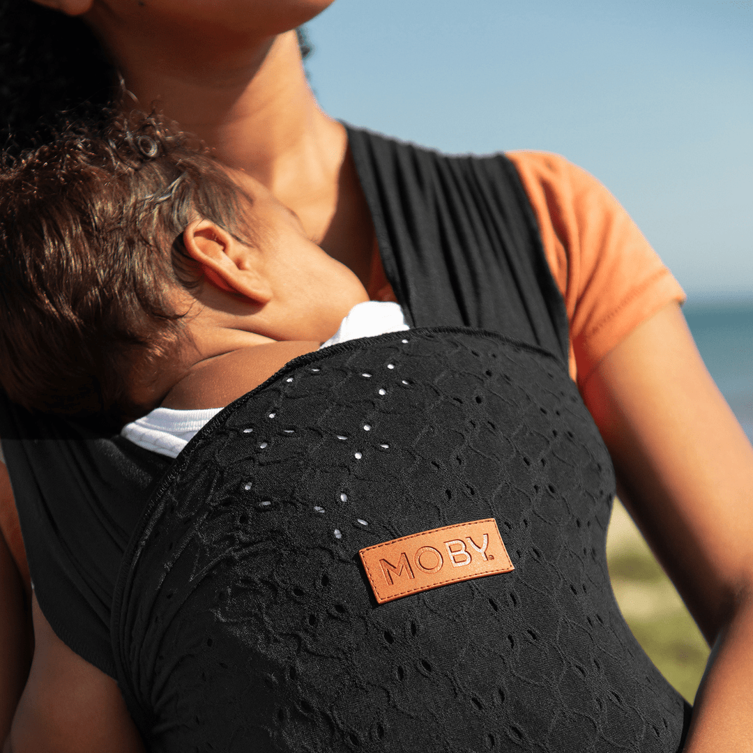 mom wearing baby in petunia x moby easy wrap in black eyelet
