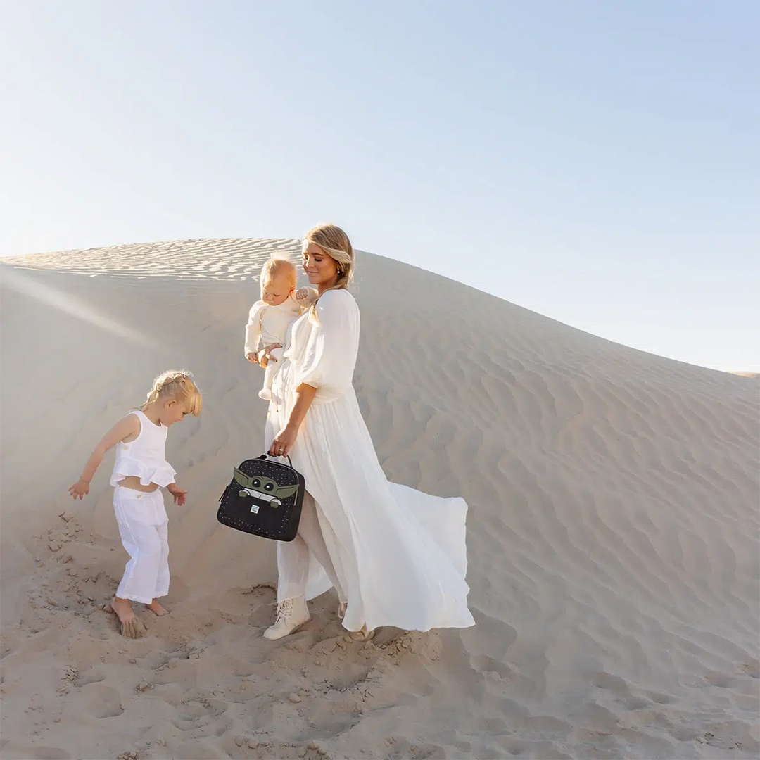 mom holding baby and the tandem bottle and lunch tote in the child while looking at girl child