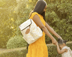 mom wearing the method backpack in whimsical belle while holding daughters' hands